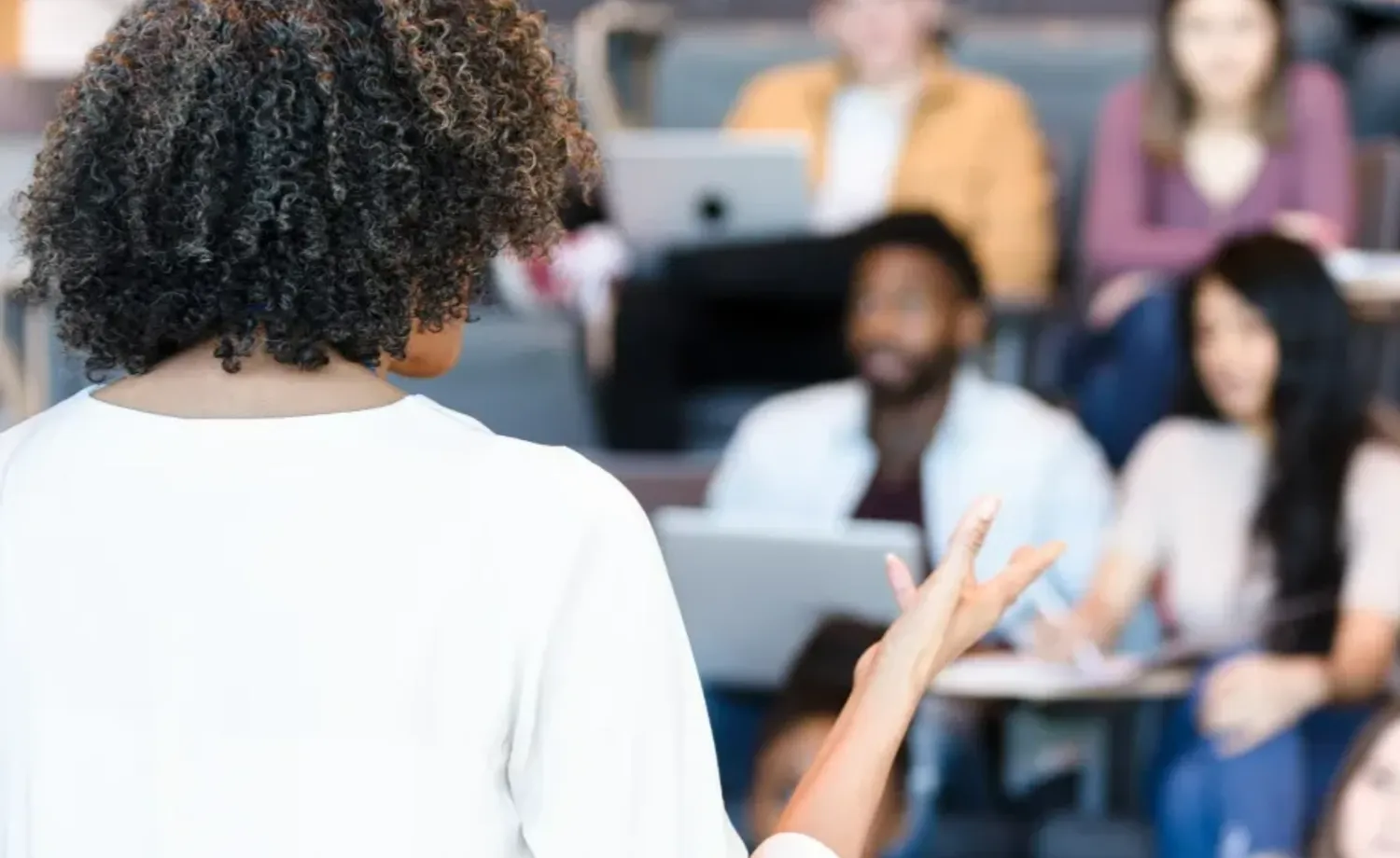 Presenter speaking to an audience in a lecture hall during a conference or educational session.