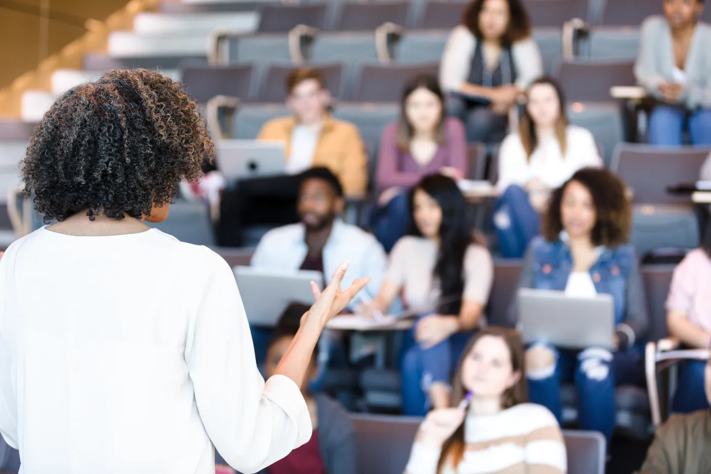 Presenter speaking to an audience in a lecture hall during a conference session.