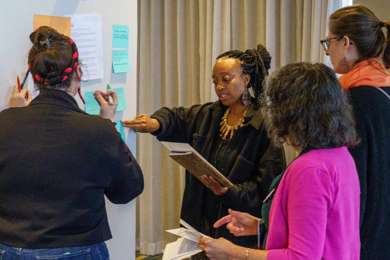 Several people stand examining papers hung on a large display board. Photo by Josh Weilepp, for the American Folklore Society.