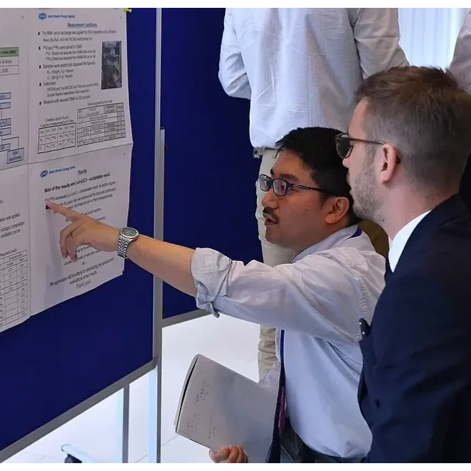 Two people looking at a conference poster, one pointing to text on the poster.