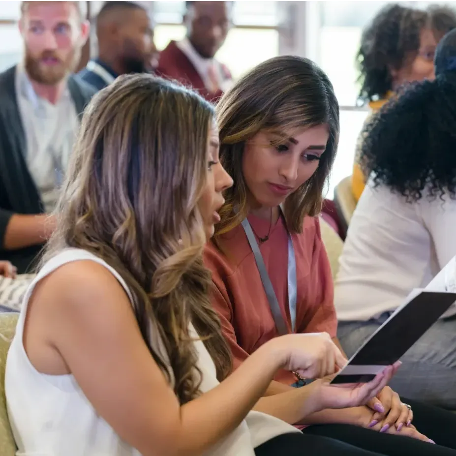 Participants engage in conversation and review conference materials during a networking session.