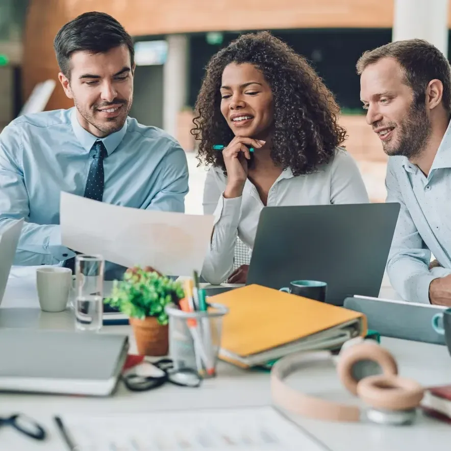 Four professionals collaborate around a table, reviewing documents and discussing ideas.