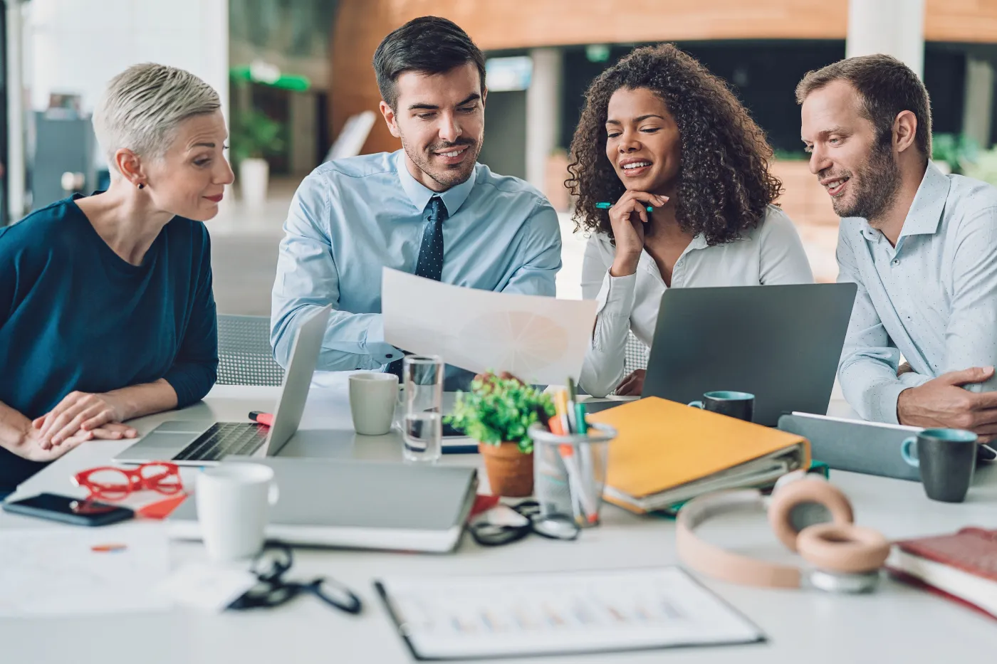 Four professionals collaborate around a table, reviewing documents and discussing ideas.