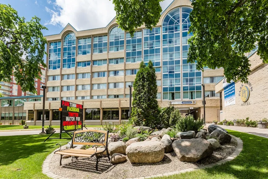 Exterior view of the Park Town Hotel, featuring a modern multi-storey building with landscaped gardens, trees, and the main entrance.
