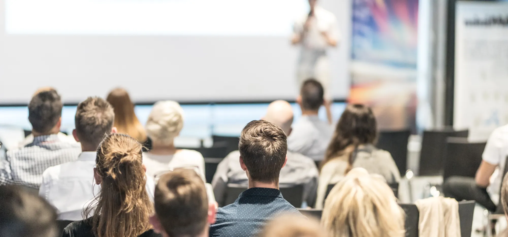 Audience members listen to a speaker during a conference presentation.