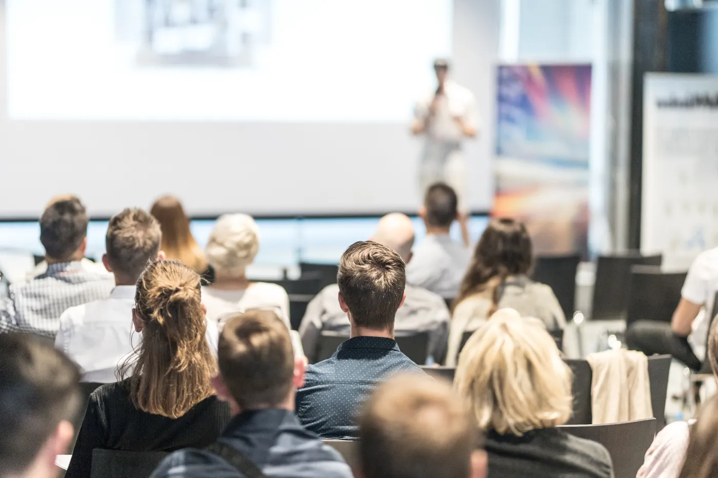 Audience members listen to a speaker during a conference presentation.