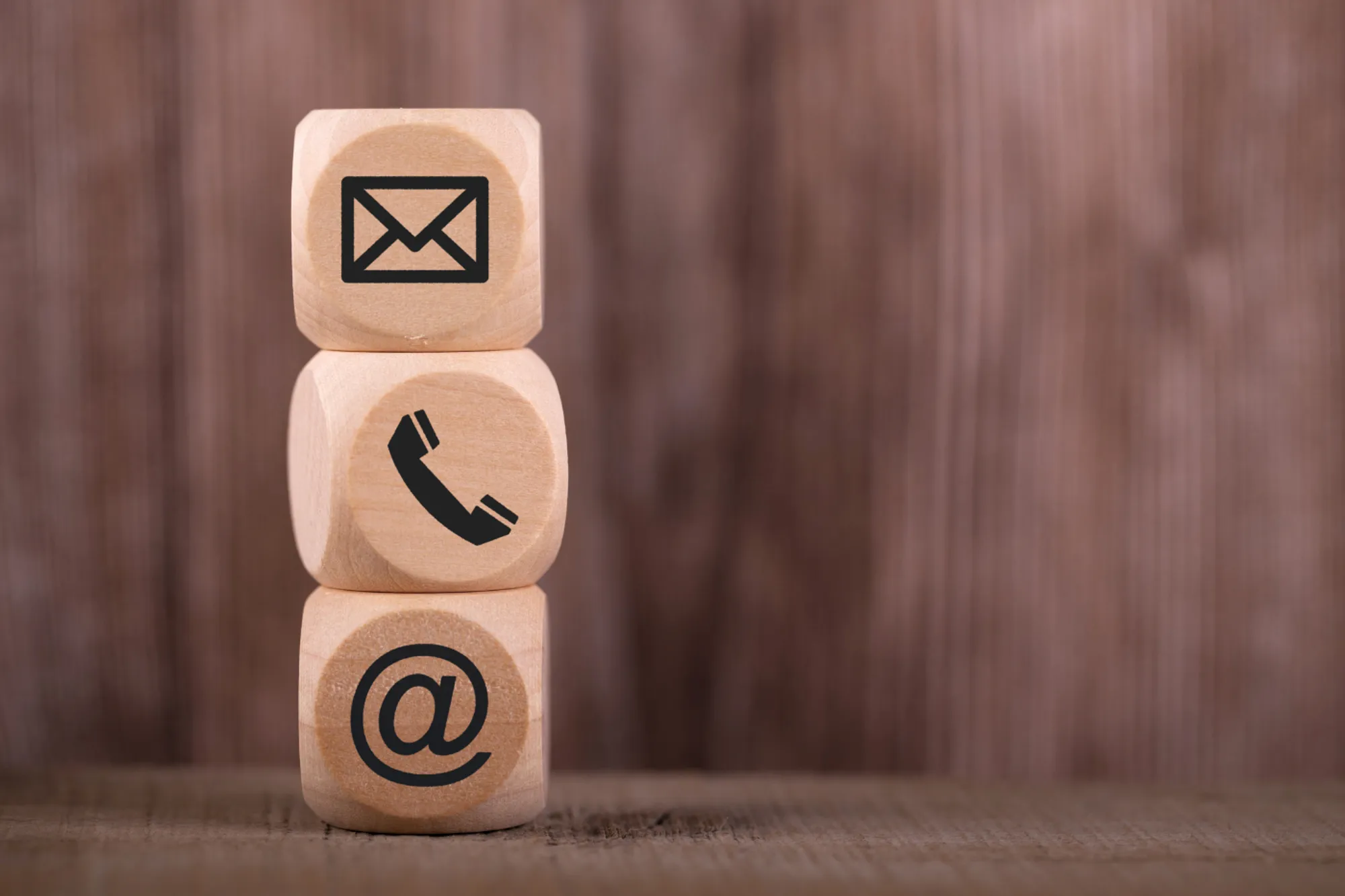Wooden blocks displaying email, phone, and contact icons, representing communication and contact information.