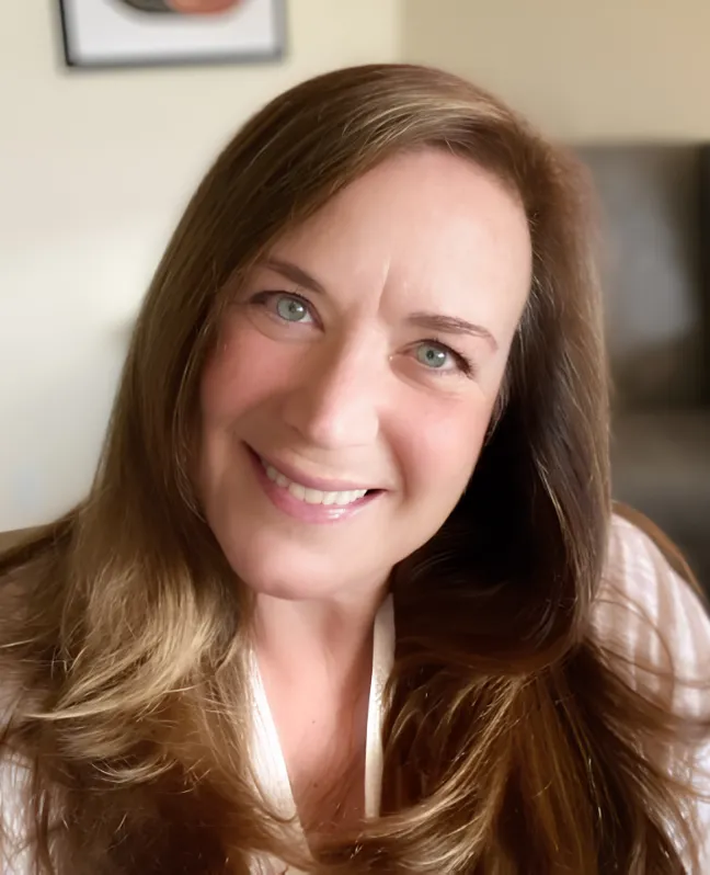 Professional headshot of a smiling woman with long brown hair.