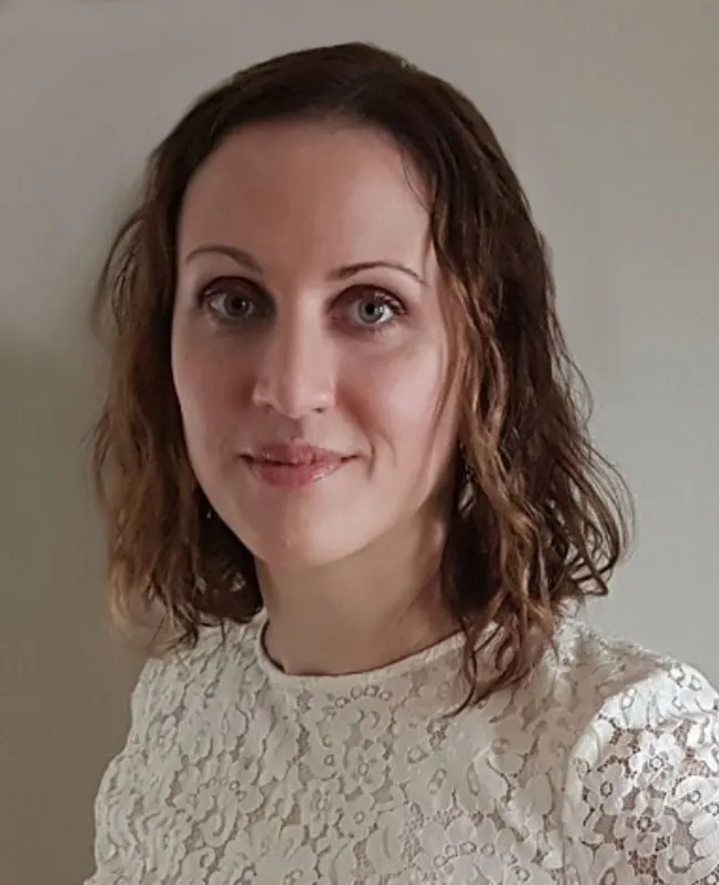 Headshot of Dr. Joelle Nadeau looking at the camera, wearing a white lace top against a neutral background.